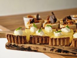 A selection of tarts with creamy filling, topped with whipped cream and garnished with mint.