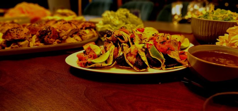 A plate of colourful tacos with fresh toppings and a side of salsa on a wooden table.